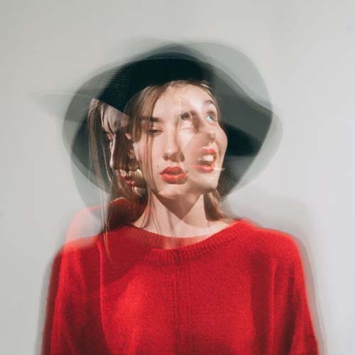woman wearing red sweater with blurred faces of different emotions of happy, sad and normal